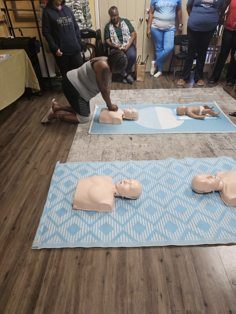 Community member practicing CPR on adult and infant mannequins during SEED Workforce Academy training